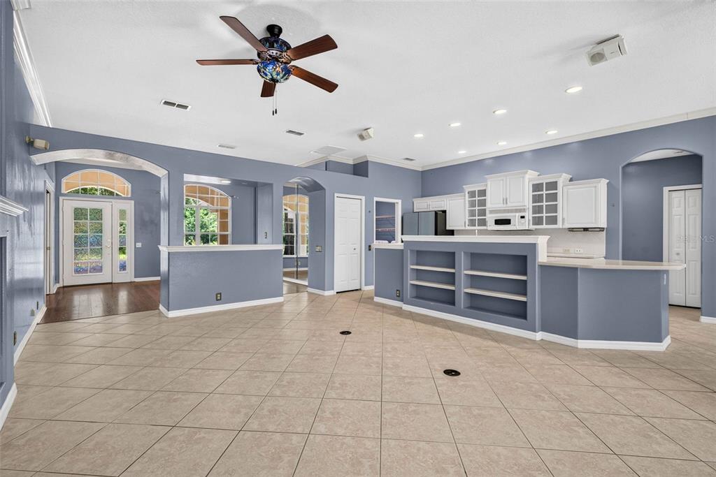 A spacious room with blue walls, tile flooring, a ceiling fan, and a kitchen area — 12 NICOTIANA COURT, HOMOSASSA, FL