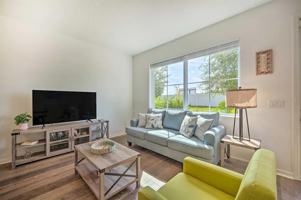 A living room features a blue sofa, a lime green armchair, and a wood media console — 709 BENOI DRIVE, DAVENPORT, FL
