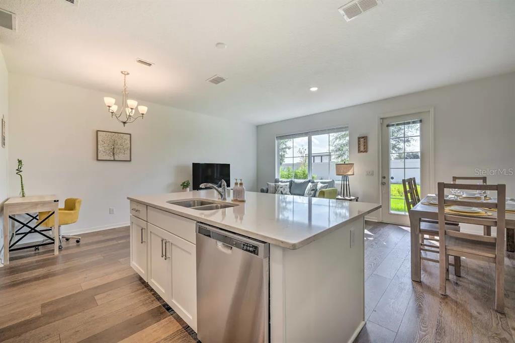 A kitchen island with a stainless steel dishwasher faces a dining area and living room — 709 BENOI DRIVE, DAVENPORT, FL