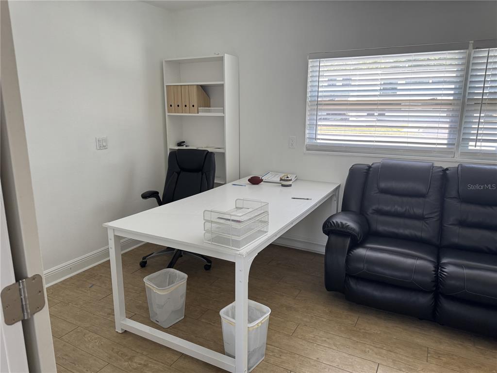 A home office features a white desk, black office chair, black sofa, and wood-look flooring — 1240 ROGERS STREET, CLEARWATER, FL