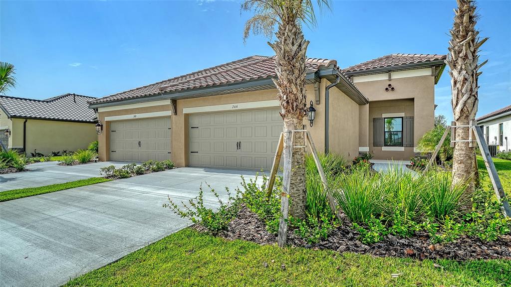 A tan single-story house with a three-car garage and two palm trees in the front yard — 264 ALTAMURA CIRCLE, NOKOMIS, FL