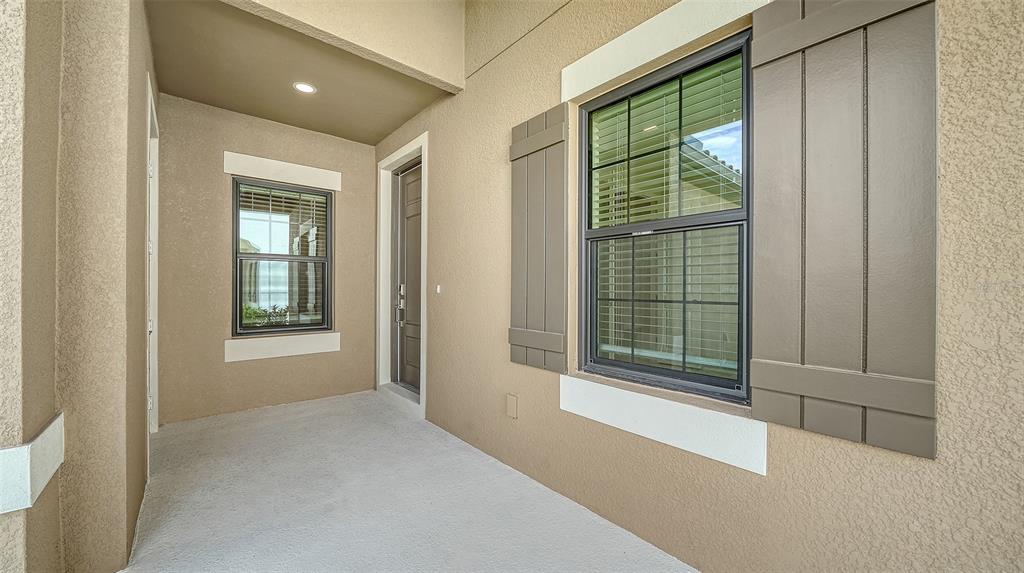 A covered entryway features a concrete floor, a front door, and a window with shutters — 264 ALTAMURA CIRCLE, NOKOMIS, FL