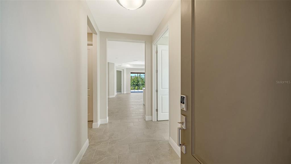 A view from an entryway looking down a tiled hallway toward a sunlit living area — 264 ALTAMURA CIRCLE, NOKOMIS, FL
