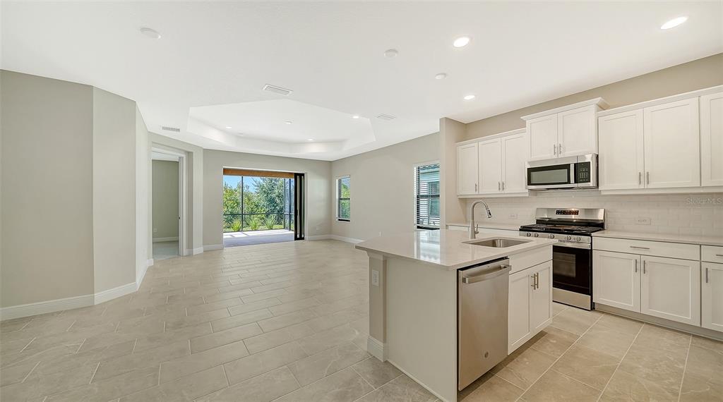 A modern kitchen with white cabinets and a center island opens to a living area — 264 ALTAMURA CIRCLE, NOKOMIS, FL