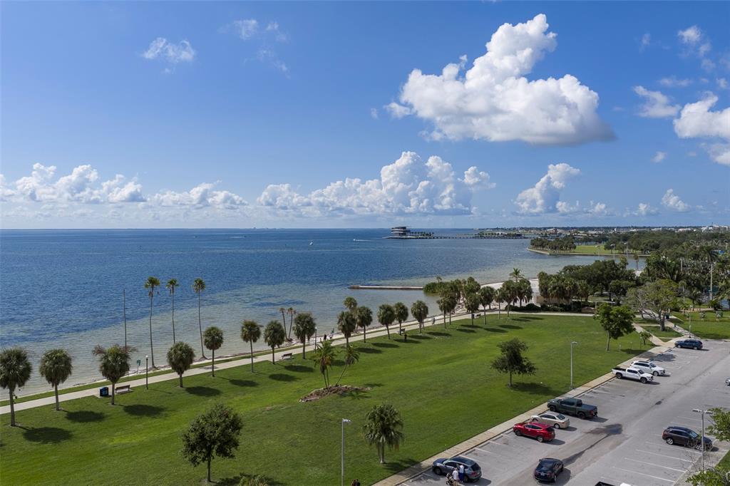 An elevated view of a waterfront park with palm trees, a parking lot, and ocean — 1200 N SHORE DRIVE NE UNIT 208, ST PETERSBURG, FL
