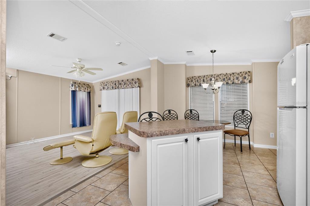 A kitchen island with white cabinets and a brown countertop sits before a dining area — 7464 DANVERS CIRCLE, PORT CHARLOTTE, FL