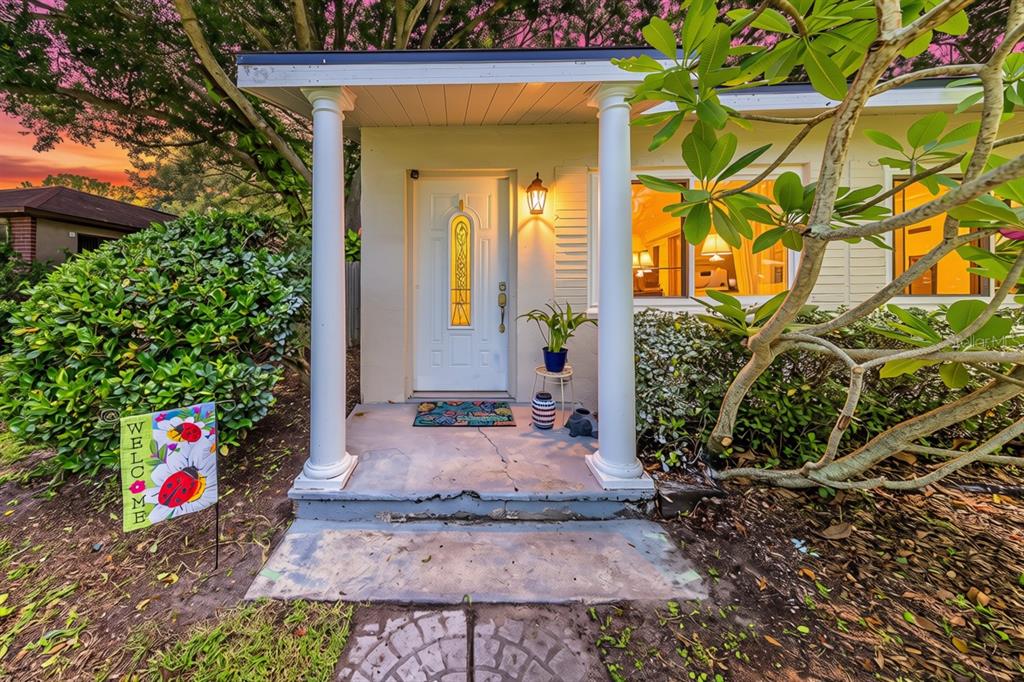 A white front door with a glass insert sits between two columns on a concrete porch — 2773 BELLE HAVEN DRIVE, CLEARWATER, FL