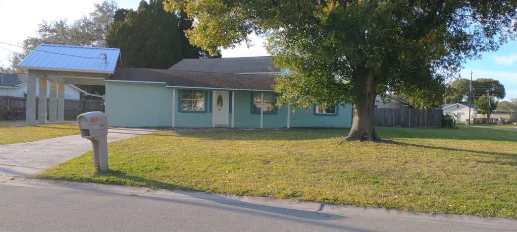 A single-story house with a light green exterior, a metal-roofed carport, and a large tree — 6224 FLORIDA DRIVE, APOLLO BEACH, FL