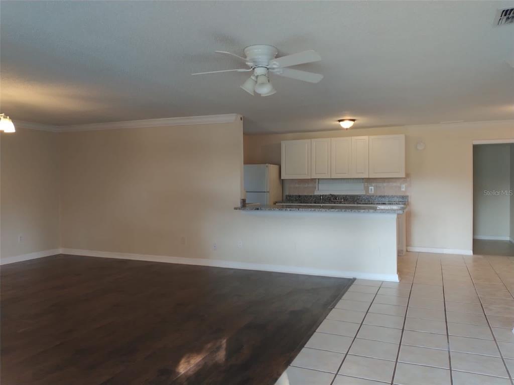 An open-concept living area with dark wood flooring, a tiled kitchen, and white cabinets — 6224 FLORIDA DRIVE, APOLLO BEACH, FL