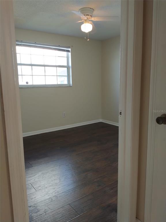 A bedroom features dark wood-look flooring, beige walls, a window with blinds, and a ceiling fan — 6224 FLORIDA DRIVE, APOLLO BEACH, FL