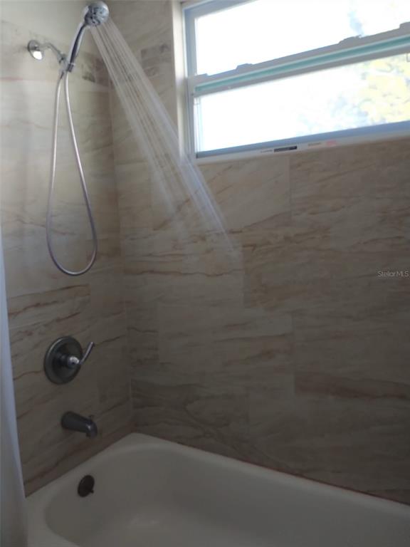 A tiled bathtub and shower combination features a handheld showerhead and a window — 6224 FLORIDA DRIVE, APOLLO BEACH, FL