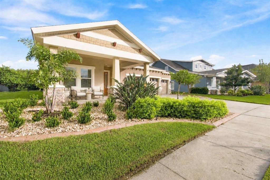 A single-story house with a covered front porch, stone accents, and a landscaped front yard — 8318 SWISS CHARD CIRCLE, LAND O LAKES, FL