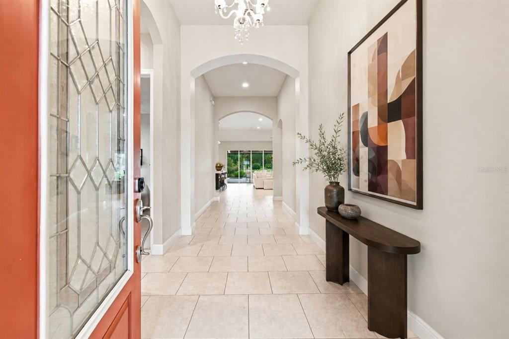 A bright entryway features tiled floors, arched ceilings, a console table, and abstract wall art — 8318 SWISS CHARD CIRCLE, LAND O LAKES, FL