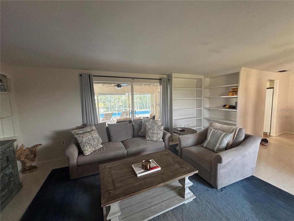 A living room features a grey sofa, armchair, wooden coffee table, and built-in shelving units — 4411 DOLPHIN LANE, PALMETTO, FL
