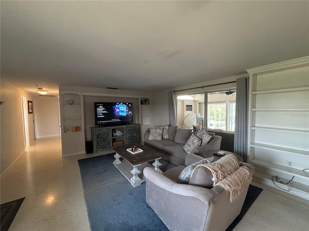 A living room features a grey sofa, matching armchair, blue area rug, and built-in shelving — 4411 DOLPHIN LANE, PALMETTO, FL