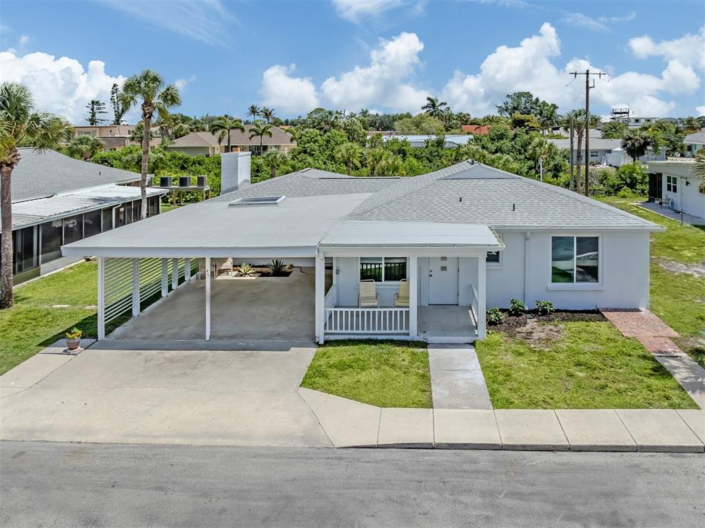 A white single-story house features a large carport, a front porch, and a shingled roof — 908 VILLAS DRIVE UNIT 45, VENICE, FL