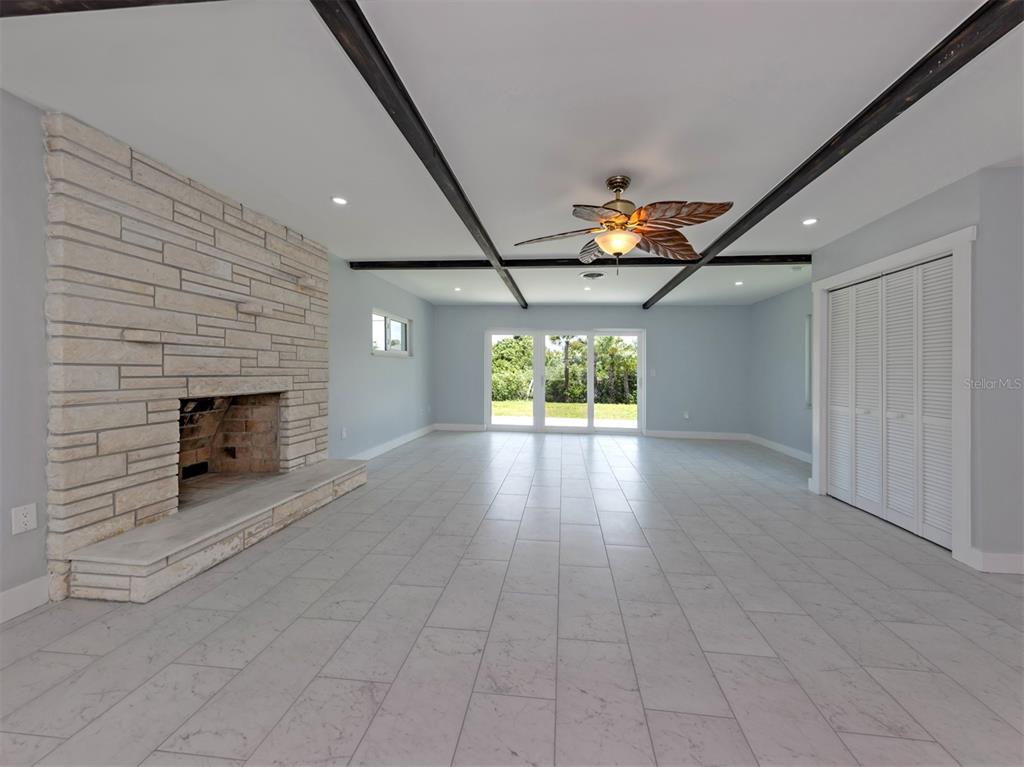 A living room features light tile floors, a stone fireplace, and dark ceiling beams — 908 VILLAS DRIVE UNIT 45, VENICE, FL