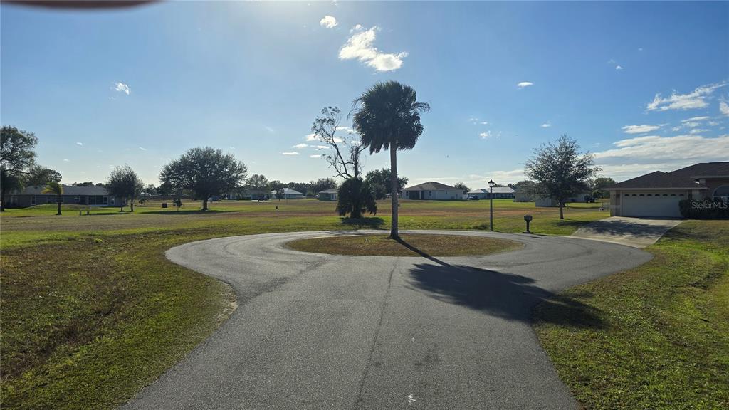 A paved circular driveway surrounds a single palm tree in a residential neighborhood — 7816 MAYA COURT, SEBRING, FL