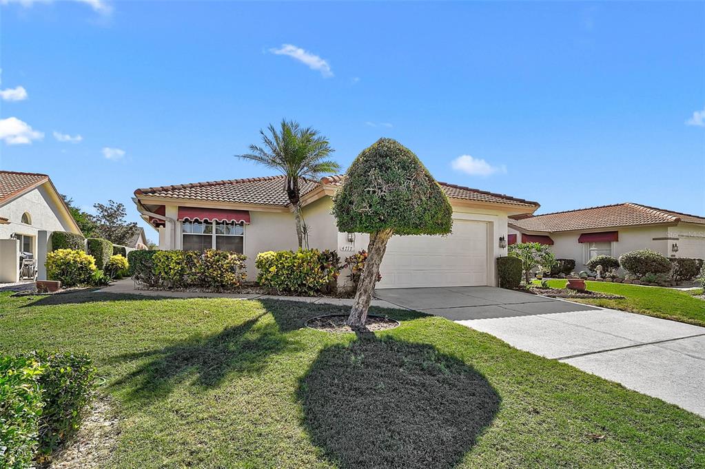 A single-story house with a tiled roof, a concrete driveway, and a manicured front lawn — 4717 PERIDIA BOULEVARD E, BRADENTON, FL