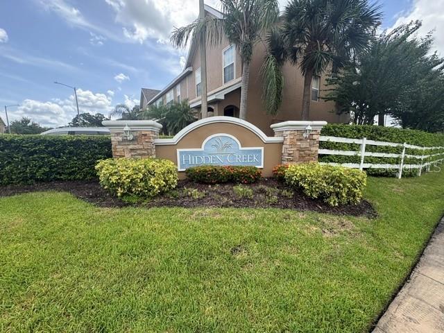 A stone monument sign for Hidden Creek sits in front of a multi-story apartment building — 6547 BLACK MANGROVE DRIVE, LARGO, FL