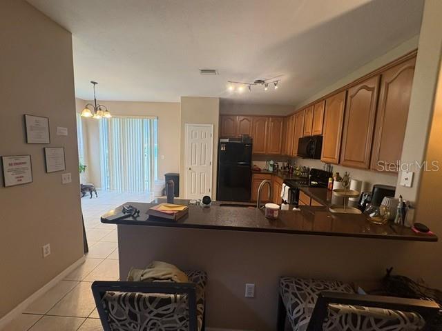 A kitchen with wood cabinets, black appliances, and a breakfast bar overlooking a dining area — 6547 BLACK MANGROVE DRIVE, LARGO, FL