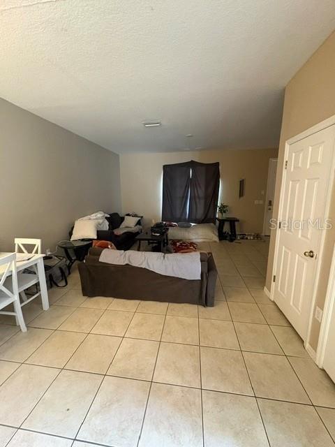 A living room with tile flooring, a sofa, and a dining table near a white door — 6547 BLACK MANGROVE DRIVE, LARGO, FL