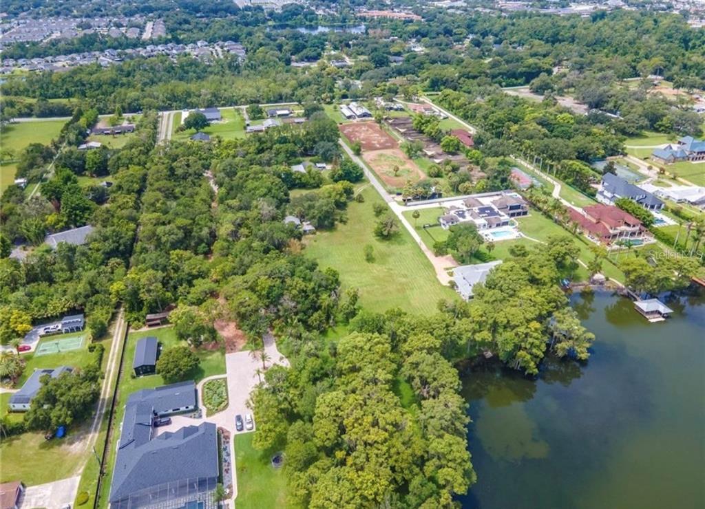 An aerial view shows several houses, large grassy lots, and a lake with docks — 1133 BELLA LAGO COVE, WINTER PARK, FL
