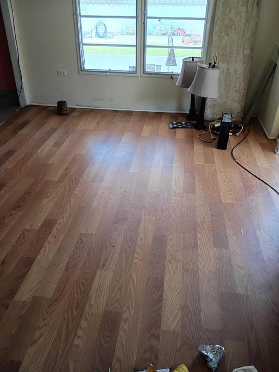 An empty room features light-colored wood-look flooring, two table lamps, and a large window — 980 7 STREET NW UNIT 55, LARGO, FL
