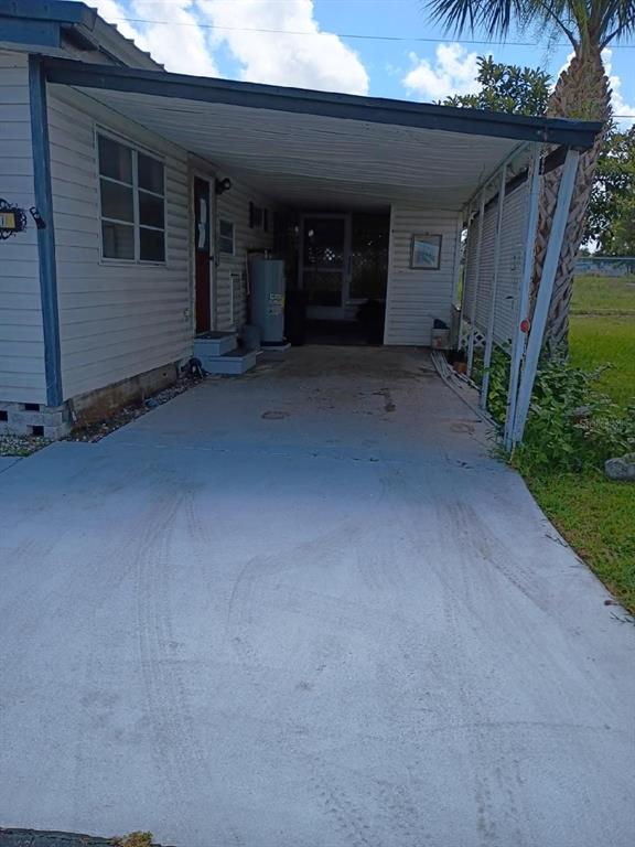 A concrete driveway leads to a covered carport attached to the side of a mobile home — 980 7 STREET NW UNIT 55, LARGO, FL
