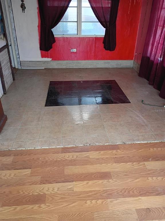 A room features a wood-look floor transitioning to beige tiles with a dark tiled center — 980 7 STREET NW UNIT 55, LARGO, FL