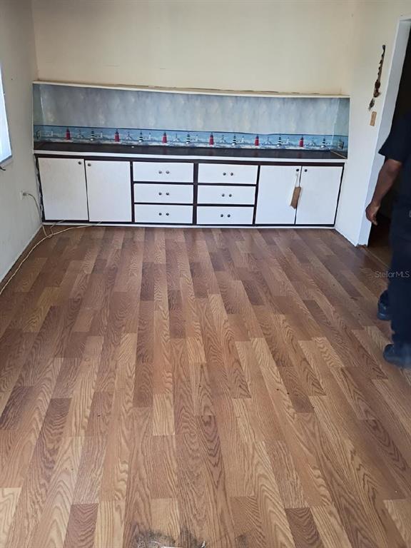 A room with wood-look flooring features a long built-in cabinet with a lighthouse-themed backsplash — 980 7 STREET NW UNIT 55, LARGO, FL
