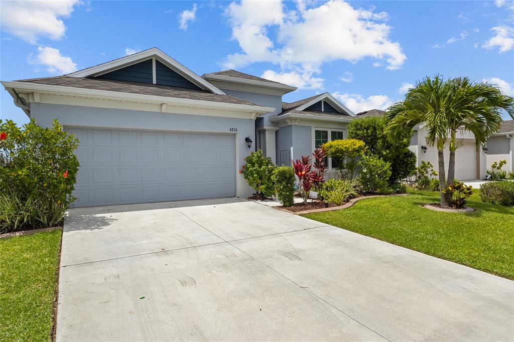 A light blue single-story house features a two-car garage, a concrete driveway, and landscaping — 4836 REISSWOOD LOOP, PALMETTO, FL