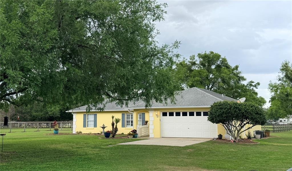A yellow single-story house with a white garage door sits on a grassy lawn — 331 SE HIGHWAY 42, SUMMERFIELD, FL