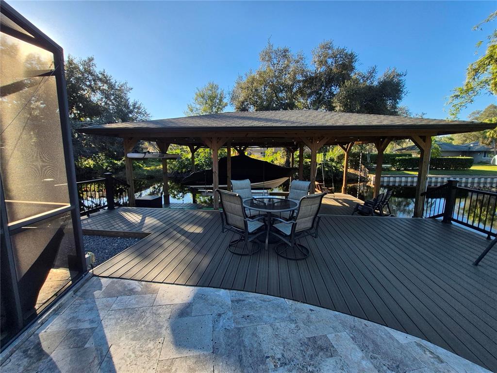 A wooden deck with a dining set overlooks a covered boat slip on a canal — 5370 WHISPERING PINE CIRCLE, ST CLOUD, FL