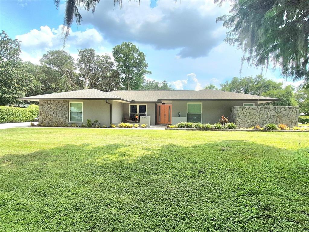 A single-story house with a stone facade, gray exterior, and a large front lawn — 5370 WHISPERING PINE CIRCLE, ST CLOUD, FL