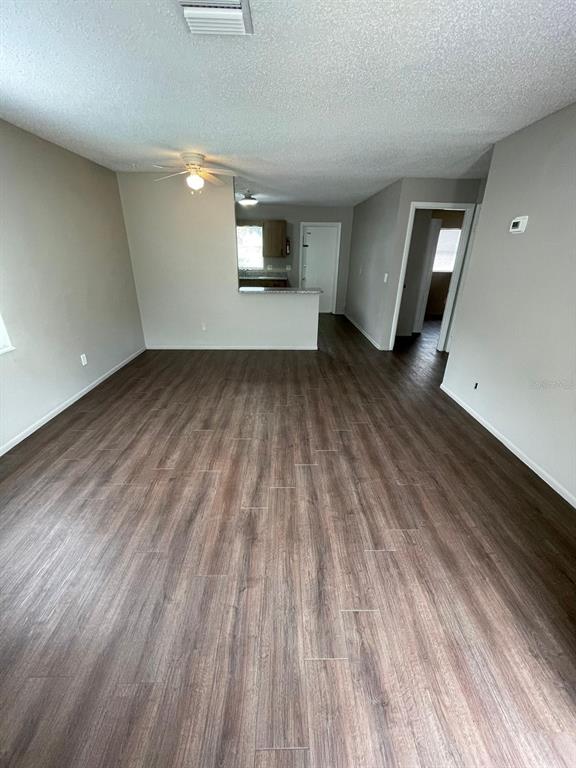 A living room with wood-look flooring, a ceiling fan, and an open kitchen pass-through — 160 N NEKOMA AVENUE UNIT 1, LAKE ALFRED, FL