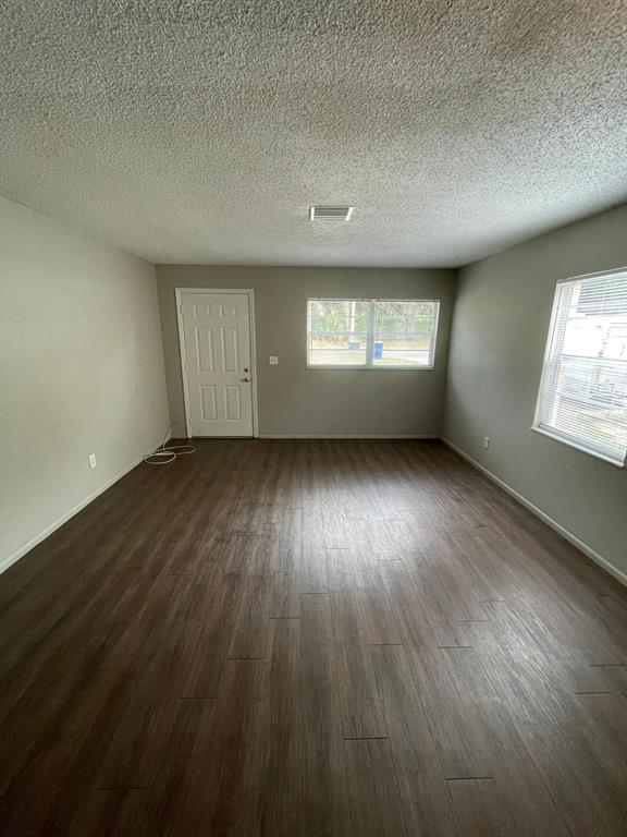An empty living room features light gray walls, dark wood-look flooring, and two windows — 160 N NEKOMA AVENUE UNIT 1, LAKE ALFRED, FL