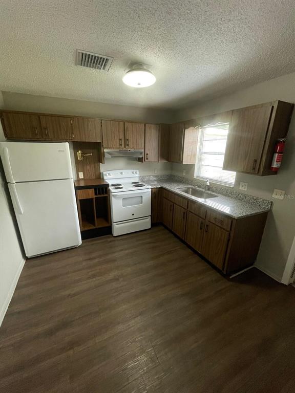 A kitchen with wood cabinets, white appliances, granite countertops, and wood-look flooring — 160 N NEKOMA AVENUE UNIT 1, LAKE ALFRED, FL