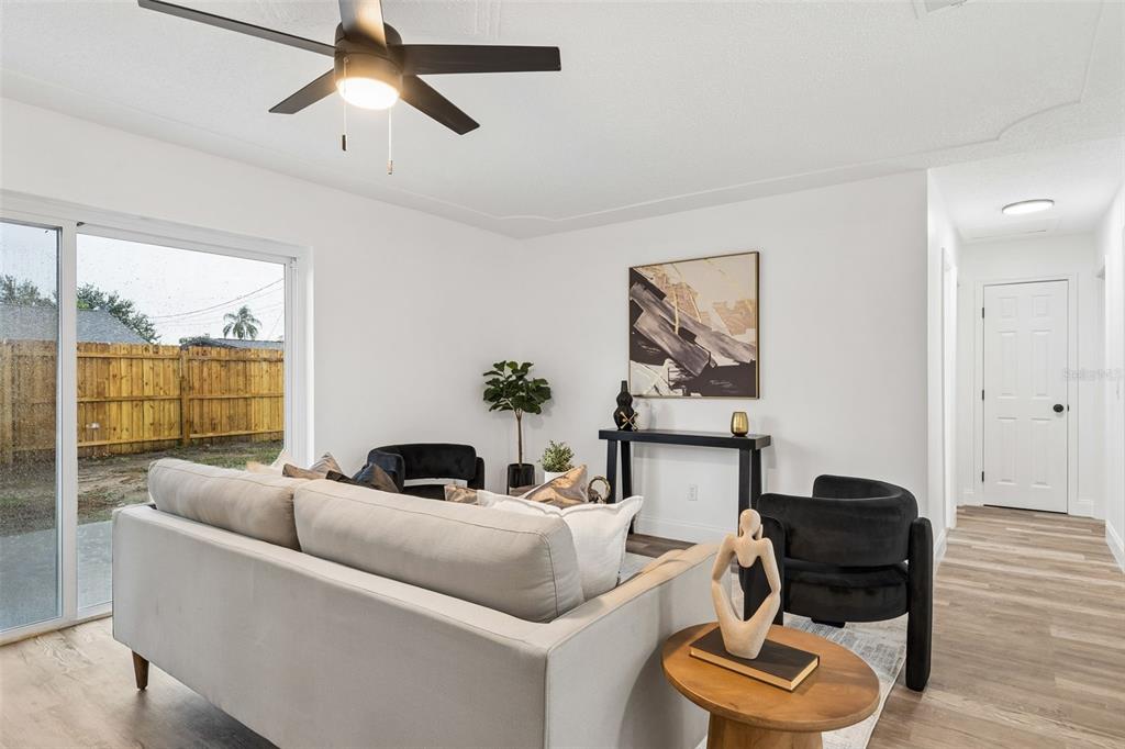 A living room features a light sofa, two black chairs, a console table, and sliding doors — 996 SARAZEN DRIVE, ROCKLEDGE, FL