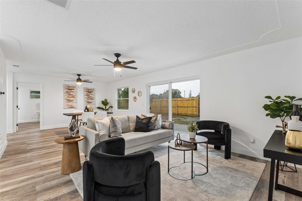 A living and dining area features light wood-look flooring, white walls, and two ceiling fans — 996 SARAZEN DRIVE, ROCKLEDGE, FL