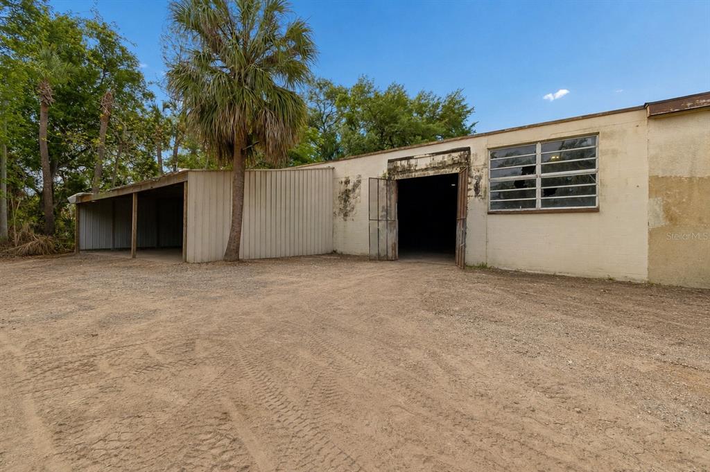 A dirt lot sits in front of a beige industrial building with an open bay — 4214 W VIRGINIA AVENUE UNIT 10, TAMPA, FL