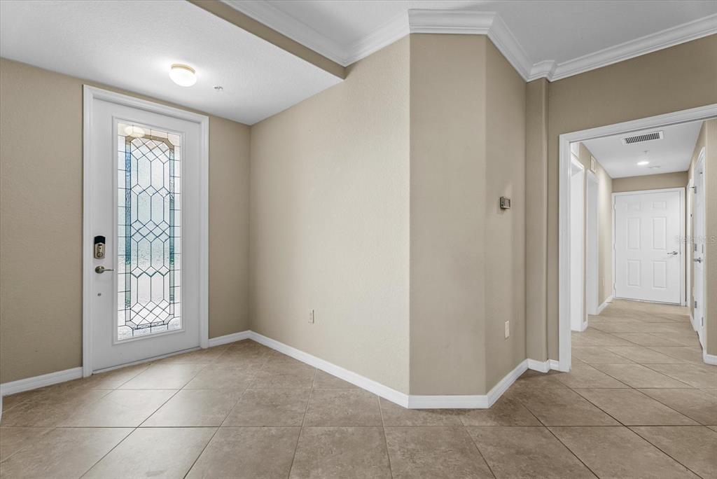 An entryway with tile flooring, a glass-paneled front door, and a hallway leading further inside — 20150 RAGAZZA CIRCLE UNIT 102, VENICE, FL