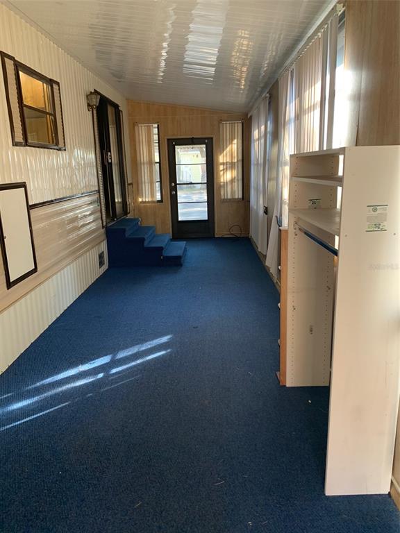 A sunroom with blue carpeting, wood-paneled walls, a white ceiling, and a set of steps — 3000 CLARCONA ROAD UNIT 616, APOPKA, FL