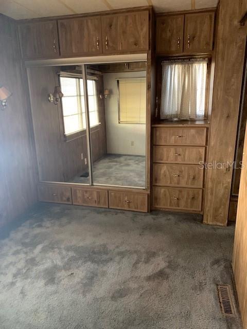 A long, narrow room with blue carpeting, wood-paneled walls, and a door leading outside — 3000 CLARCONA ROAD UNIT 616, APOPKA, FL