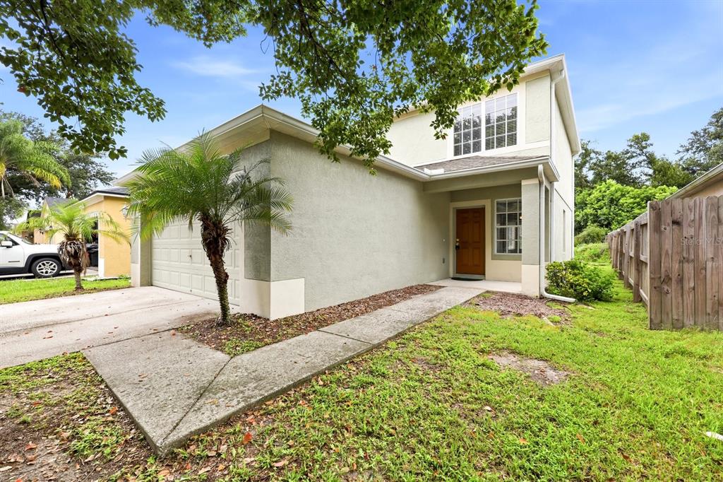 A two-story stucco house with a garage, a palm tree, and a wooden fence — 1717 MOSAIC FOREST DRIVE, SEFFNER, FL