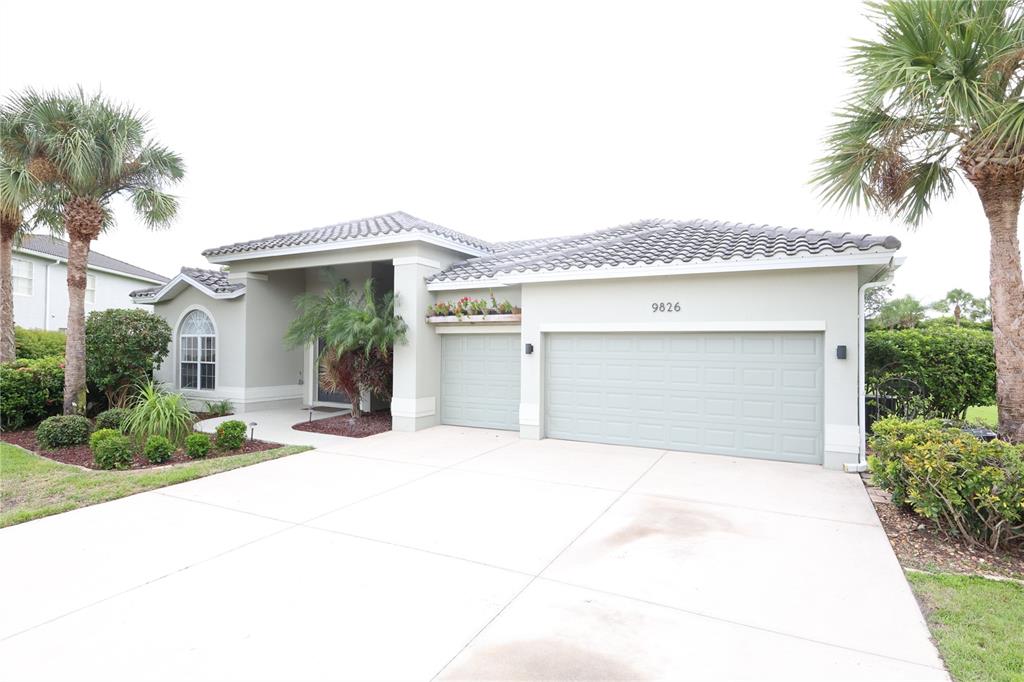 A single-story house with a three-car garage, light-colored stucco exterior, and two palm trees — 9826 WEATHER STONE PLACE, FORT MYERS, FL