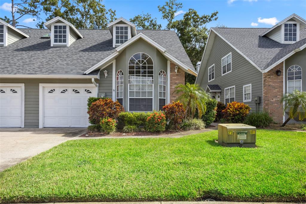 A two-story house with green siding, a white garage door, and multiple dormer windows — 2740 HAMBLE VILLAGE LANE, PALM HARBOR, FL