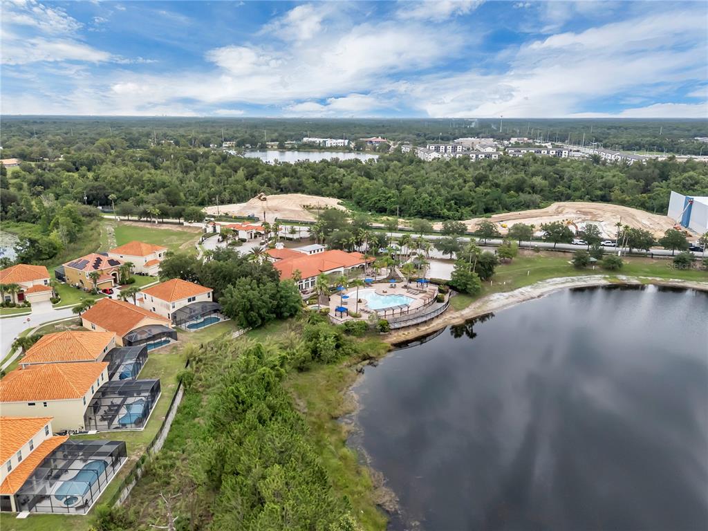 An aerial view shows a residential community with a clubhouse, swimming pool, and lake — 391 CABELLO DRIVE, DAVENPORT, FL