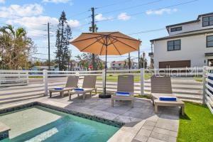 A swimming pool with lounge chairs and an umbrella on a patio near a house — 14500 N BAYSHORE DRIVE, MADEIRA BEACH, FL