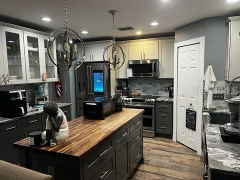 A kitchen features dark gray cabinets, a wood-topped island, and two spherical pendant lights — 1034 LAKE DOE BOULEVARD, APOPKA, FL